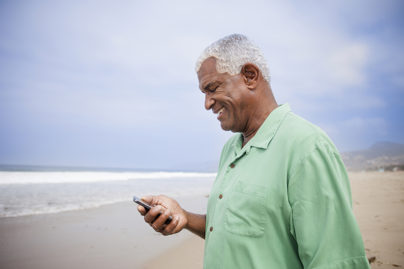 A person looking at a mobile device on a beach.