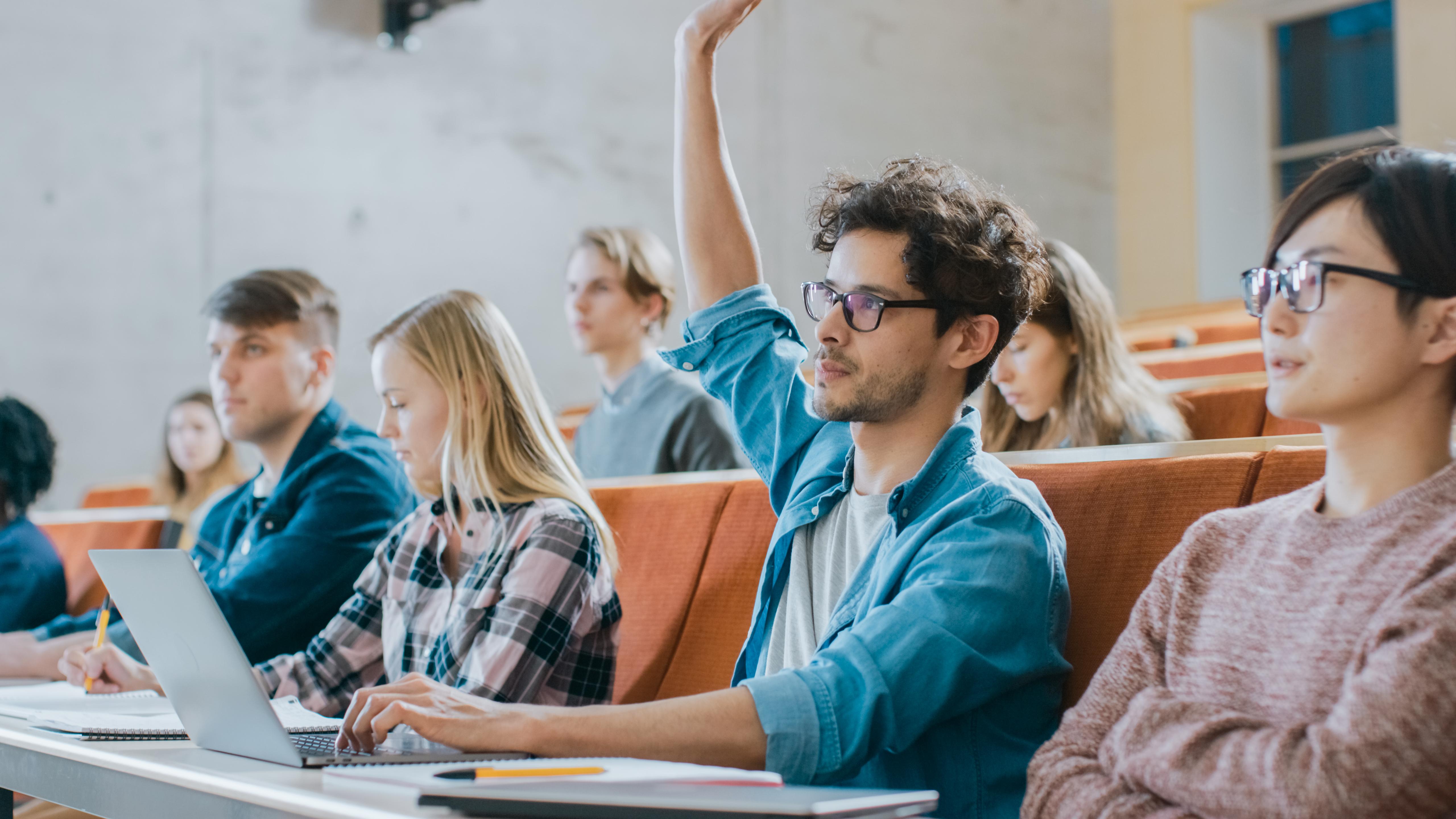 Male student raising hand in university lecture