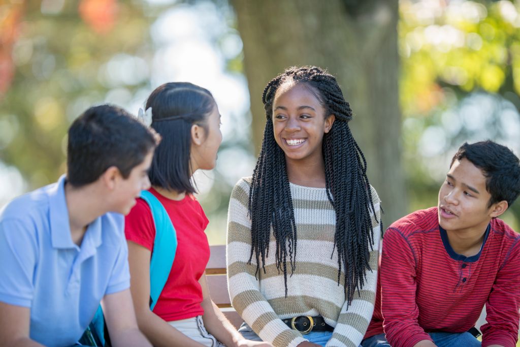 Group of kids smiling and talking to each other.