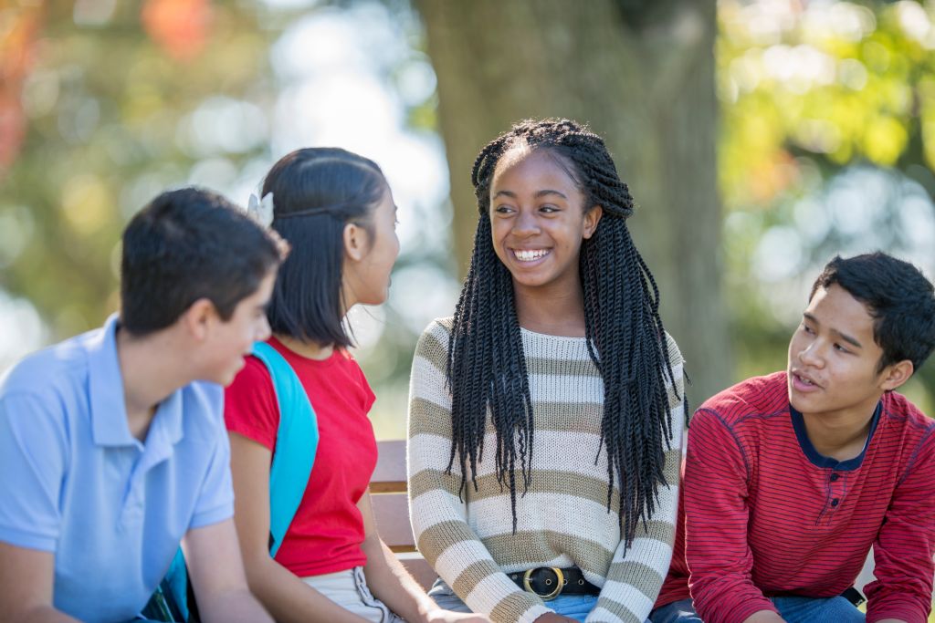 Group of kids smiling and talking to each other.