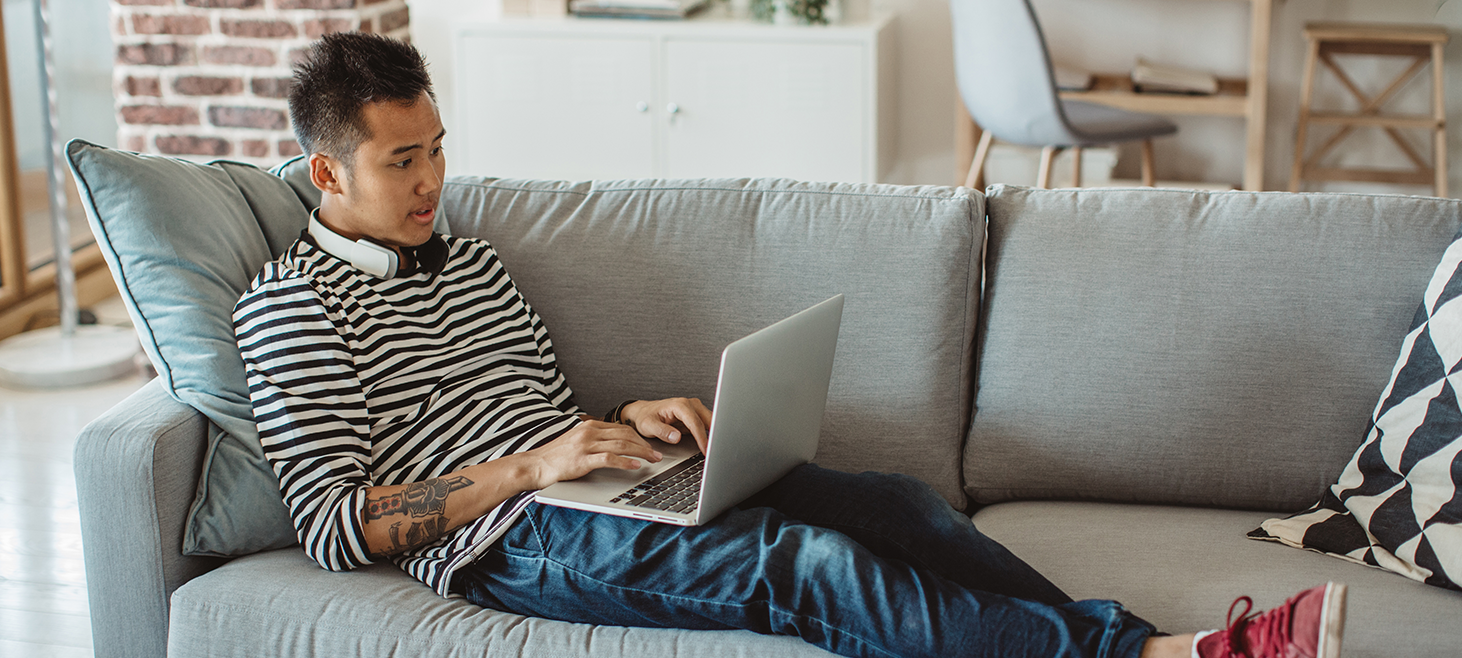 Young male sitting on the couch with his laptop