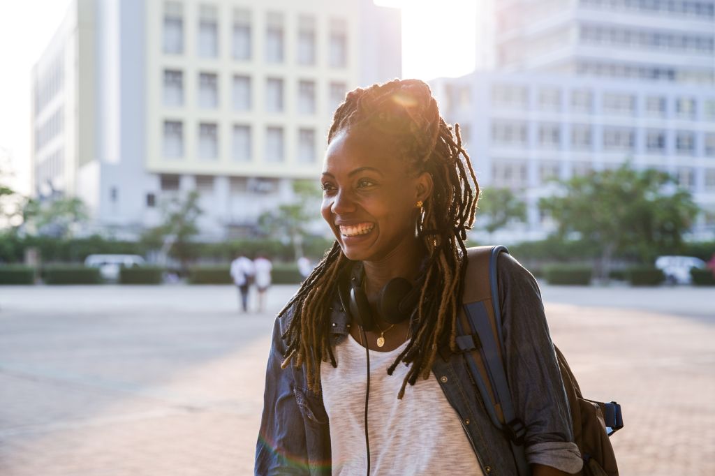 A young black woman smiling and walking in the park.