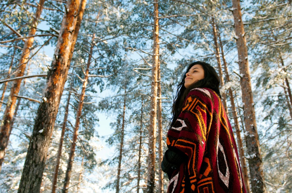 A young woman standing in the woods.