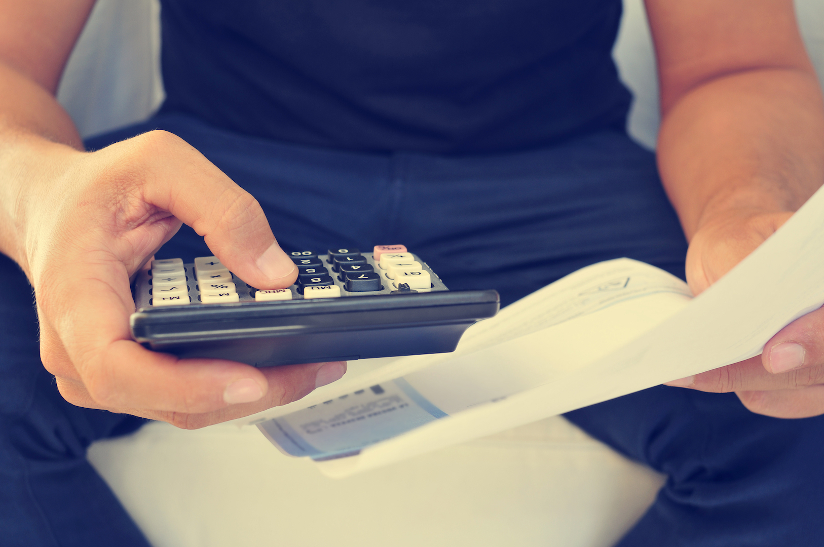 A man is using calculator and looking at cheque.