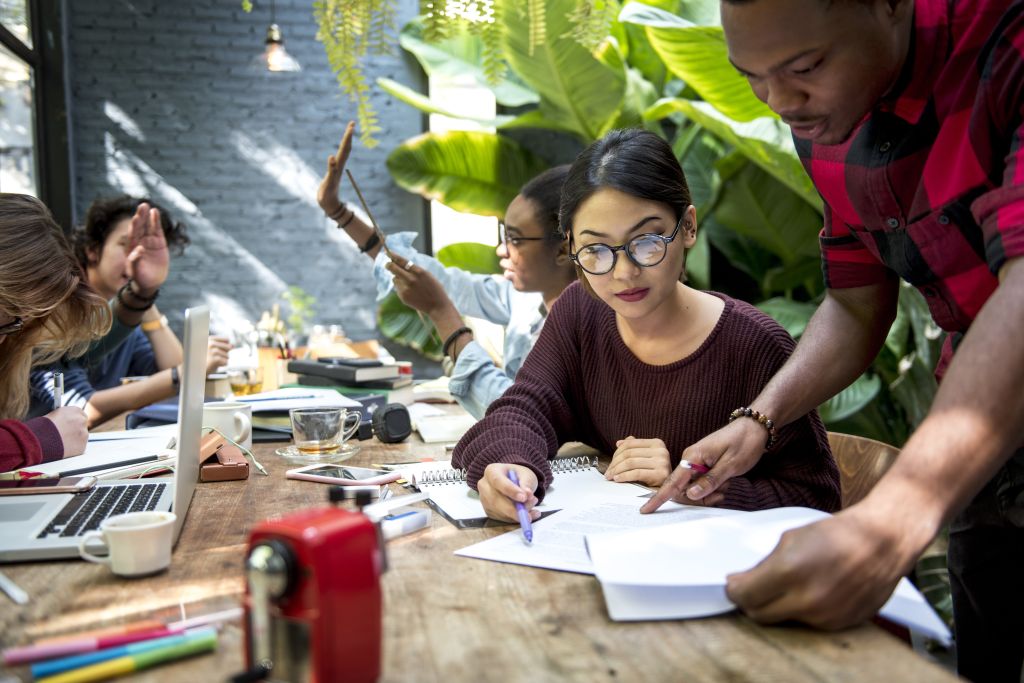 A group of people discussing work at a big desk in office.