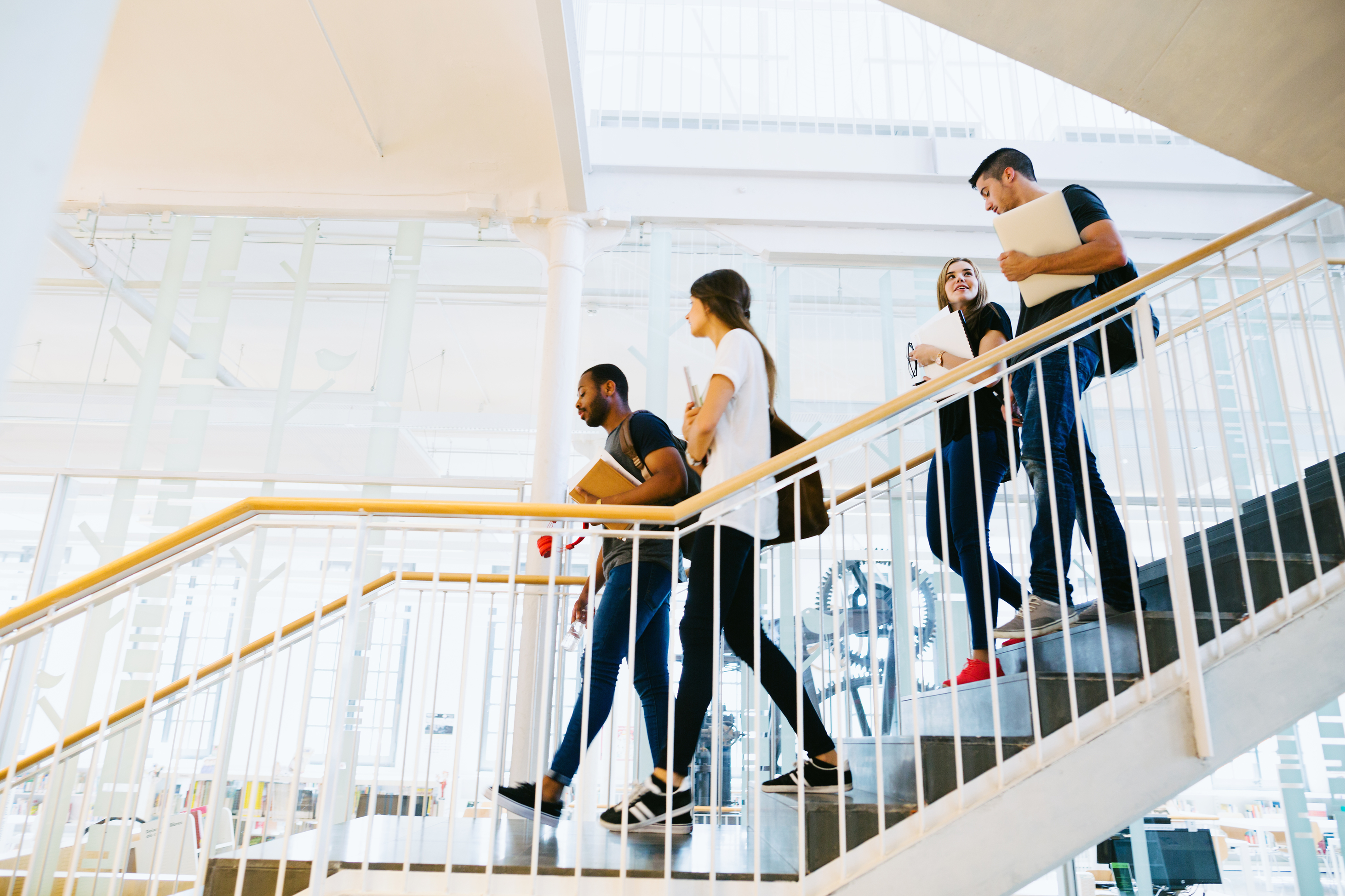 A group of college students talking and walking down the stairs.