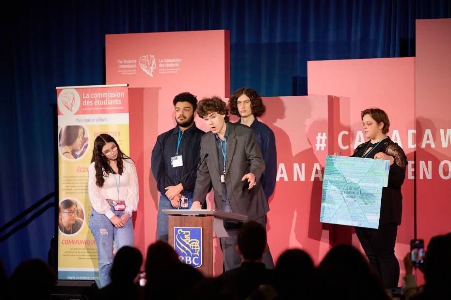 Group of youth on stage speaking into podium