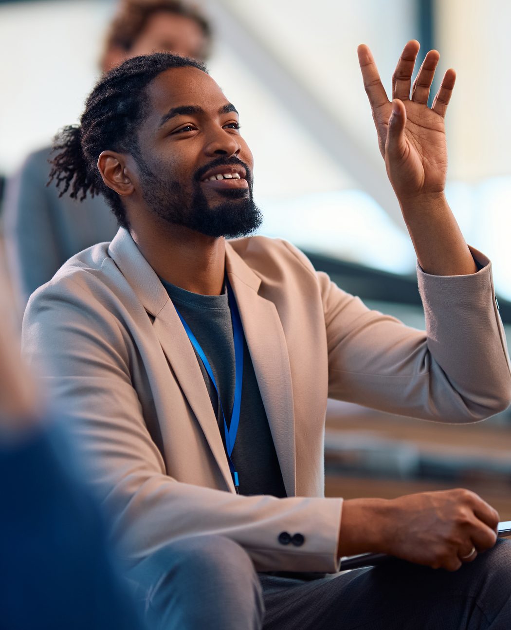 African American entrepreneur raising his arm to ask a question during a  business conference in board room.